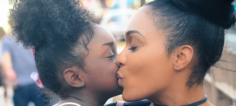 Mother kissing young daughter outdoors
