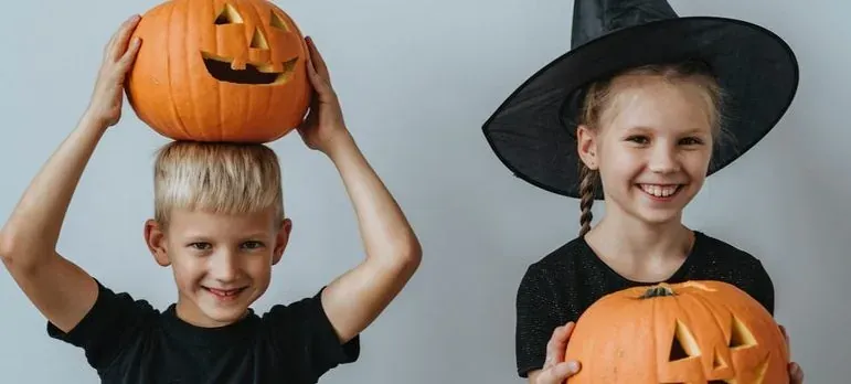 Kids in Halloween costumes with pumpkins