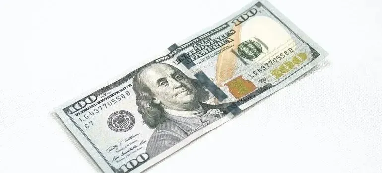 One hundred dollar bill on white fabric