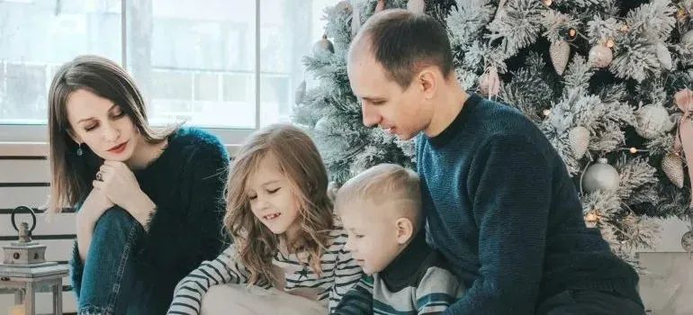 Family with two children beside decorated Christmas tree