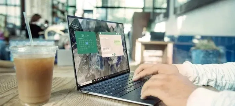 Person using laptop with calendar app in a cafe