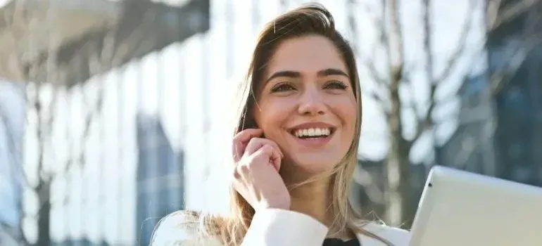 Smiling young woman talking on phone outside glass building