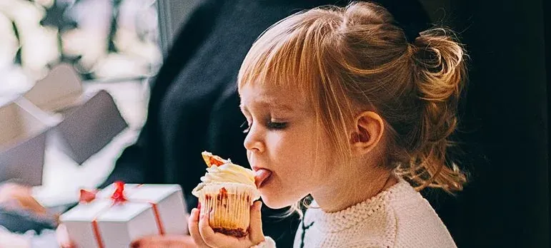 Girl licking frosting off cupcake