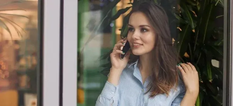 Woman talking on phone by window with plants