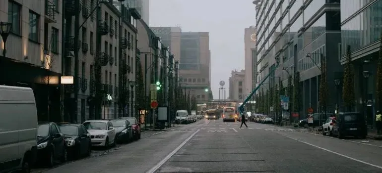 Overcast city street with parked cars and unmarked vans