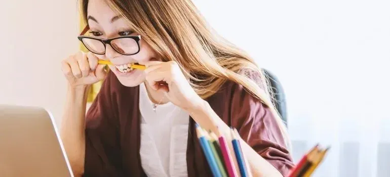 Stressed woman biting pencil in front of laptop