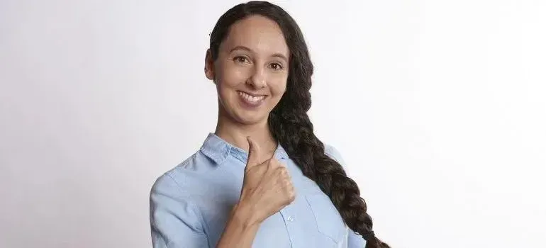 Smiling braided woman in blue shirt giving thumbs up