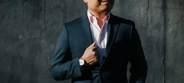 Man in navy suit posing against dark textured wall