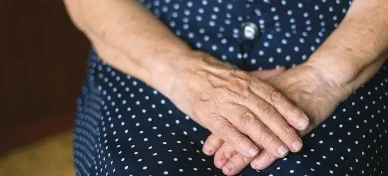 Elderly woman's folded hands on polka-dot dress