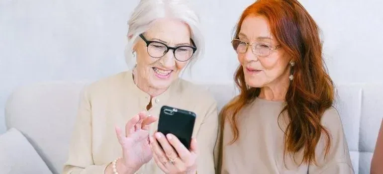 Two senior women smiling at a smartphone together
