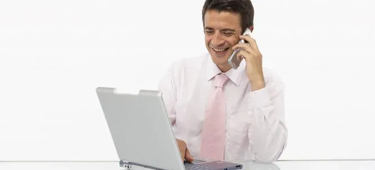 Businessman on phone with laptop, white background