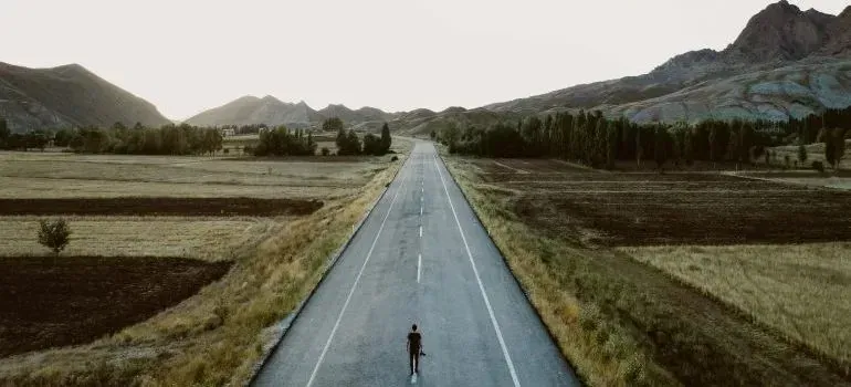 Person walking down empty road through mountain valley