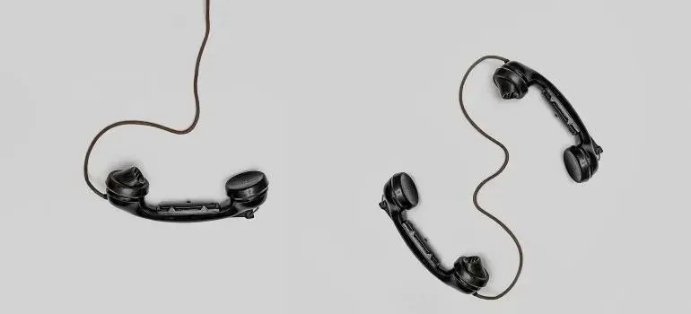 Two vintage black telephone handsets on plain background
