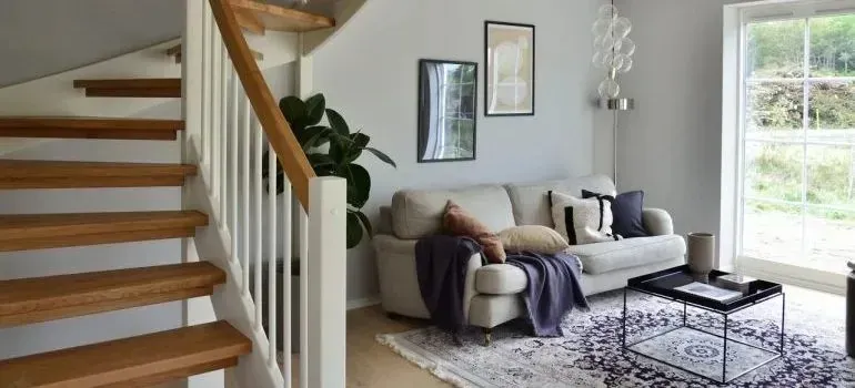 Bright living room with wooden staircase and beige sofa