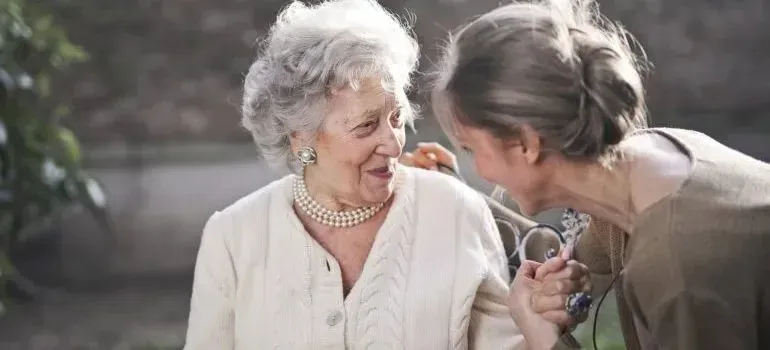 Two senior women chatting and laughing outdoors