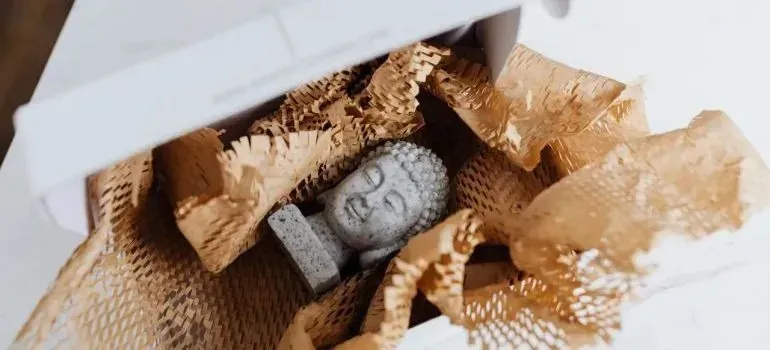 Buddha figurine nestled in shredded packing paper in box