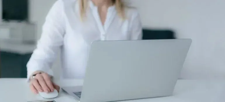 Woman in white shirt using laptop and mouse