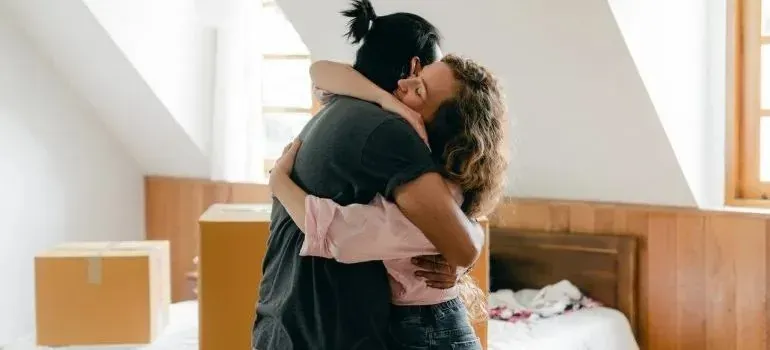 Couple hugging in bright bedroom with moving boxes