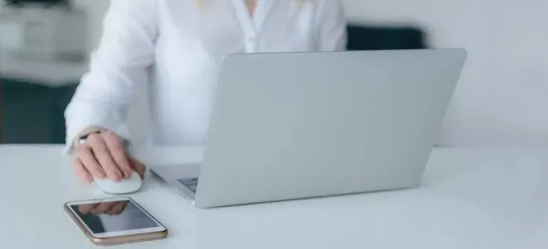 Woman using laptop and mouse at white desk