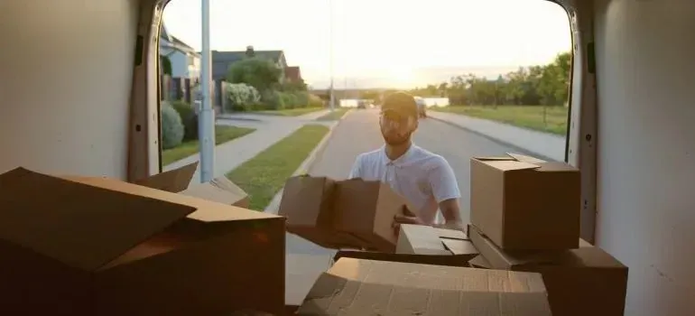 Man loading cardboard boxes into unmarked moving van