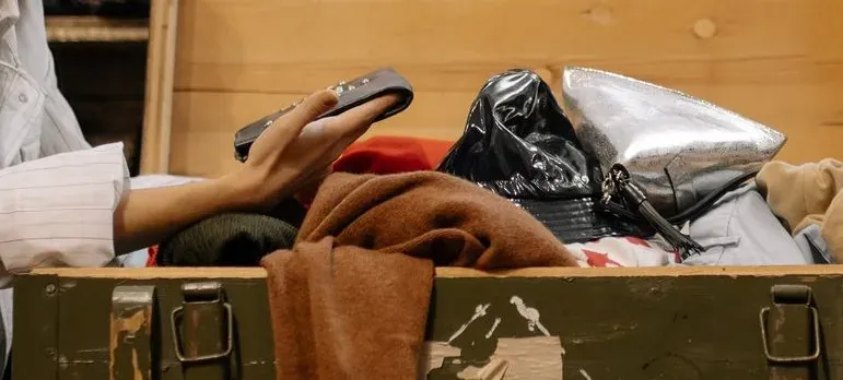 Hands sorting clothes in wooden trunk