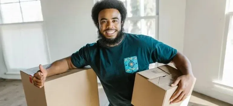 Smiling bearded man holding two cardboard moving boxes