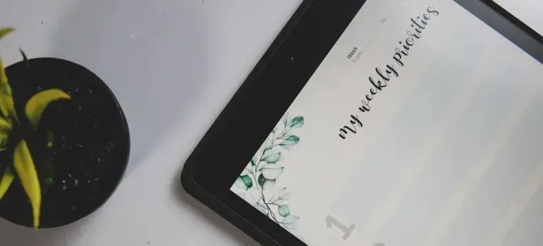Tablet displaying weekly priorities planner beside potted plant