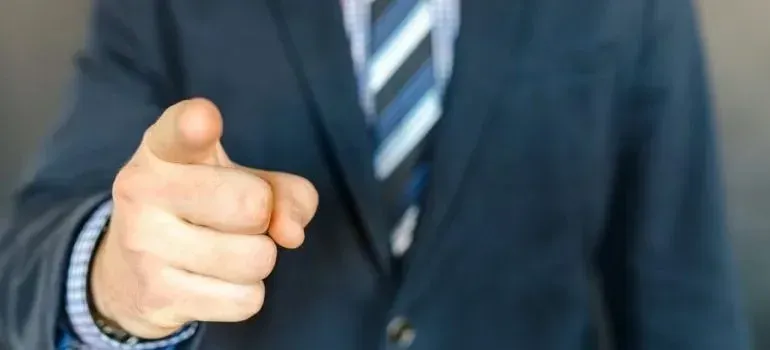 Businessman in navy suit pointing finger at camera