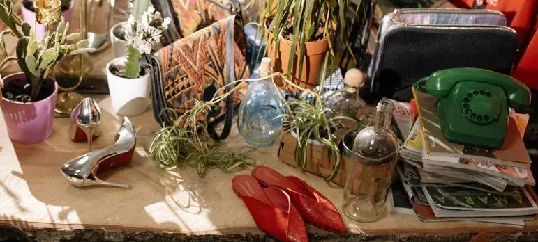 Cluttered table with shoes, plants, phone