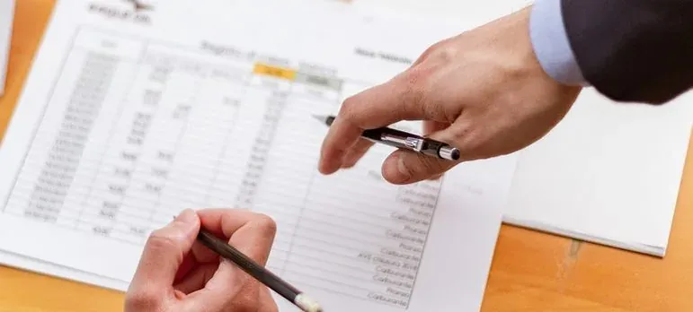 Hands with pens over spreadsheet document