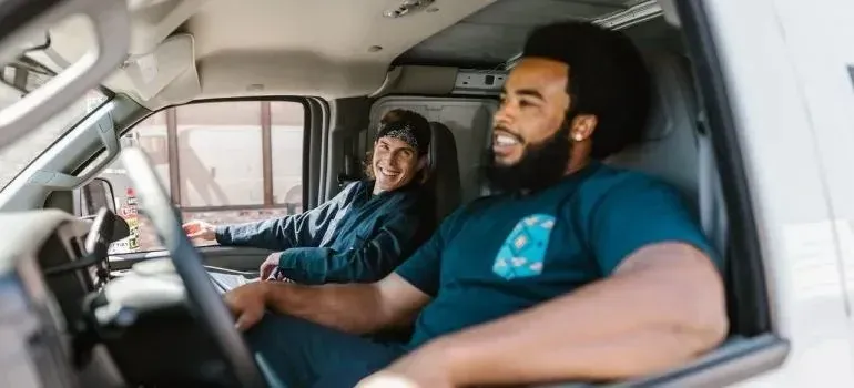 Two smiling movers sitting in moving van cab