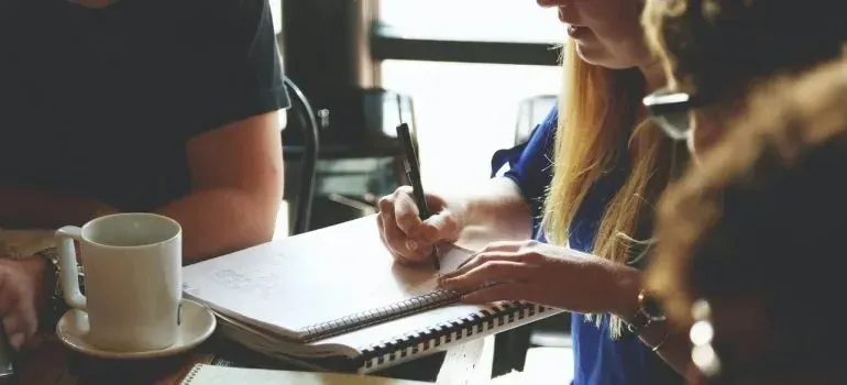 Woman writing notes in notebook during cafe meeting
