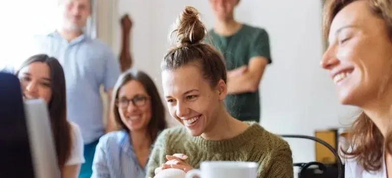 Smiling coworkers gathered around computer screen in office