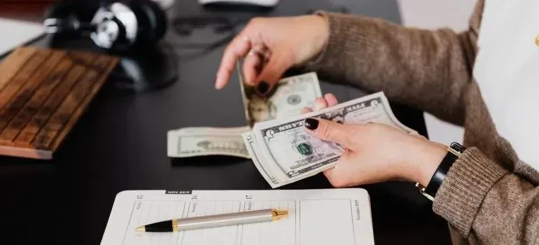 Woman counting cash over desk planner and pen