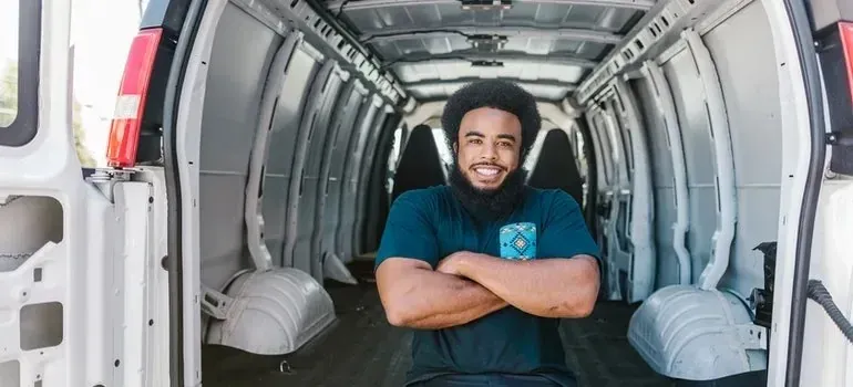Smiling mover sitting arms crossed inside empty cargo van