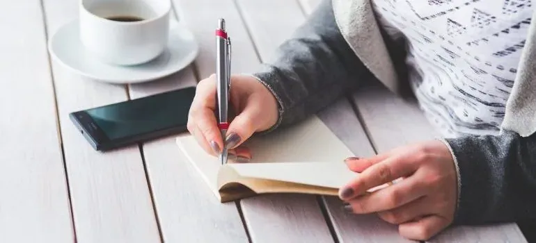 Woman writing in notebook with coffee