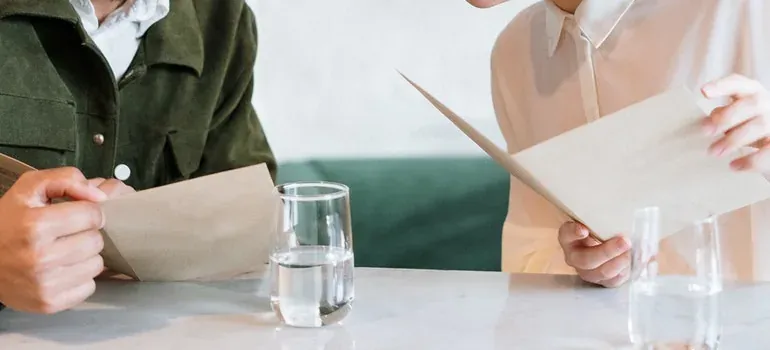 Two people holding envelopes at table