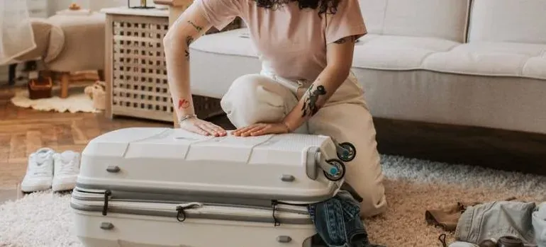 Woman closing suitcase on rug