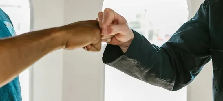 Two people fist bumping in bright white room