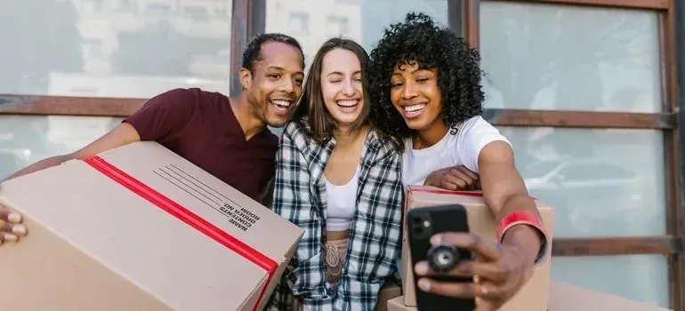 Three friends taking selfie with cardboard moving boxes