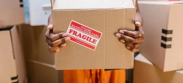 Hands holding cardboard box with red fragile sticker