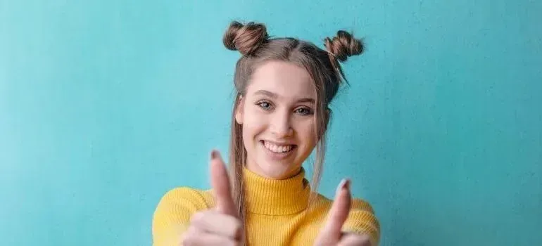 Cheerful woman in yellow sweater pointing at camera