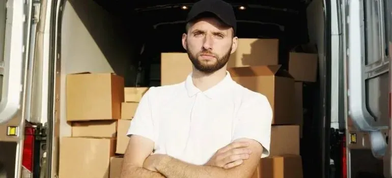 Mover in plain white polo by van full of boxes