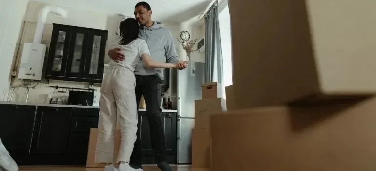 Couple dancing in kitchen surrounded by moving boxes
