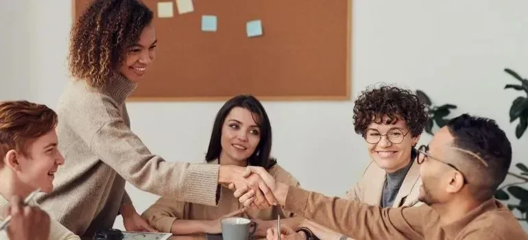 Colleagues shaking hands during office team meeting