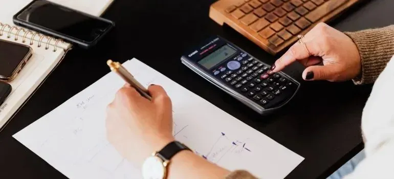 Hands writing notes and using Casio calculator, incidental product logo