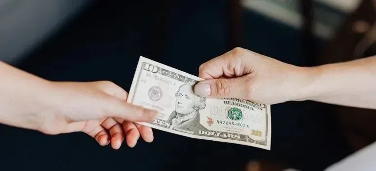 Hand passing ten-dollar bill to another person