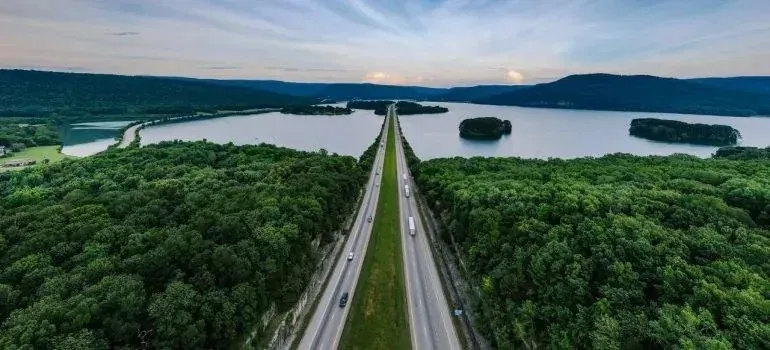 Aerial view of highway through forest toward lake