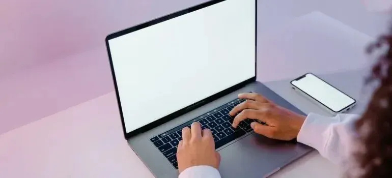 Person typing on laptop with blank white screen