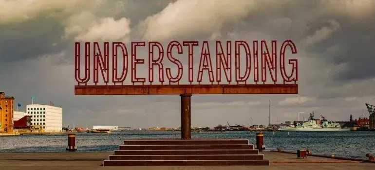 Large outdoor UNDERSTANDING sign sculpture at harbor waterfront